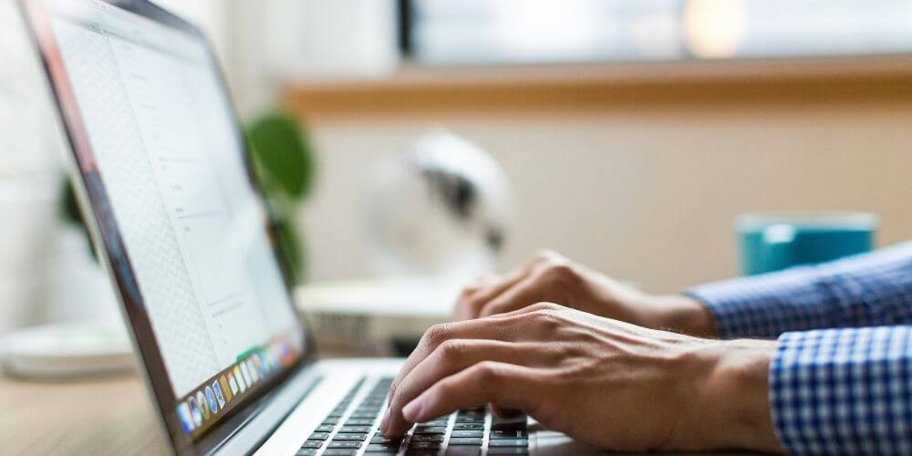 jak napisac do pracodawcy; mezczyzna siedzący przy laptopie przy oknie