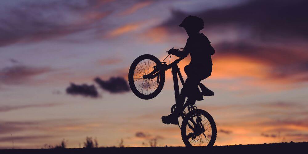 jak zwiększyć pewność siebie; chłopiec jeżdżący na jednym kole roweru