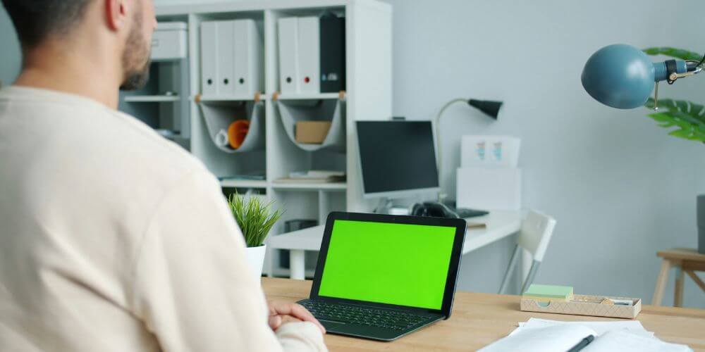 opinia klienta po programie kompas kariery; mężczyzna pracujący na laptopie z zielonym ekranem